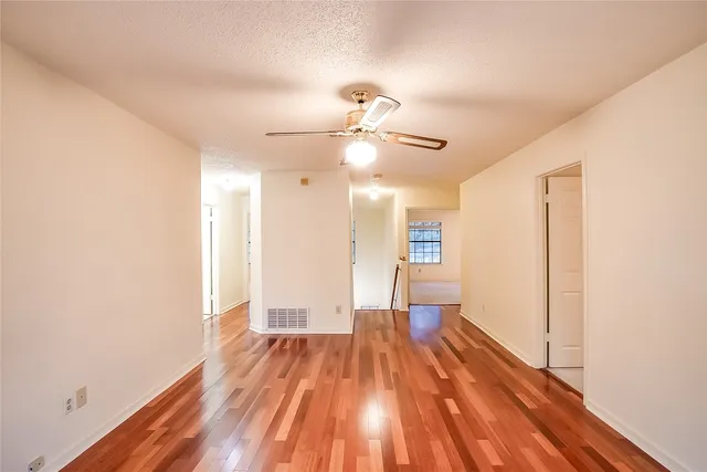 an empty room with windows and fan