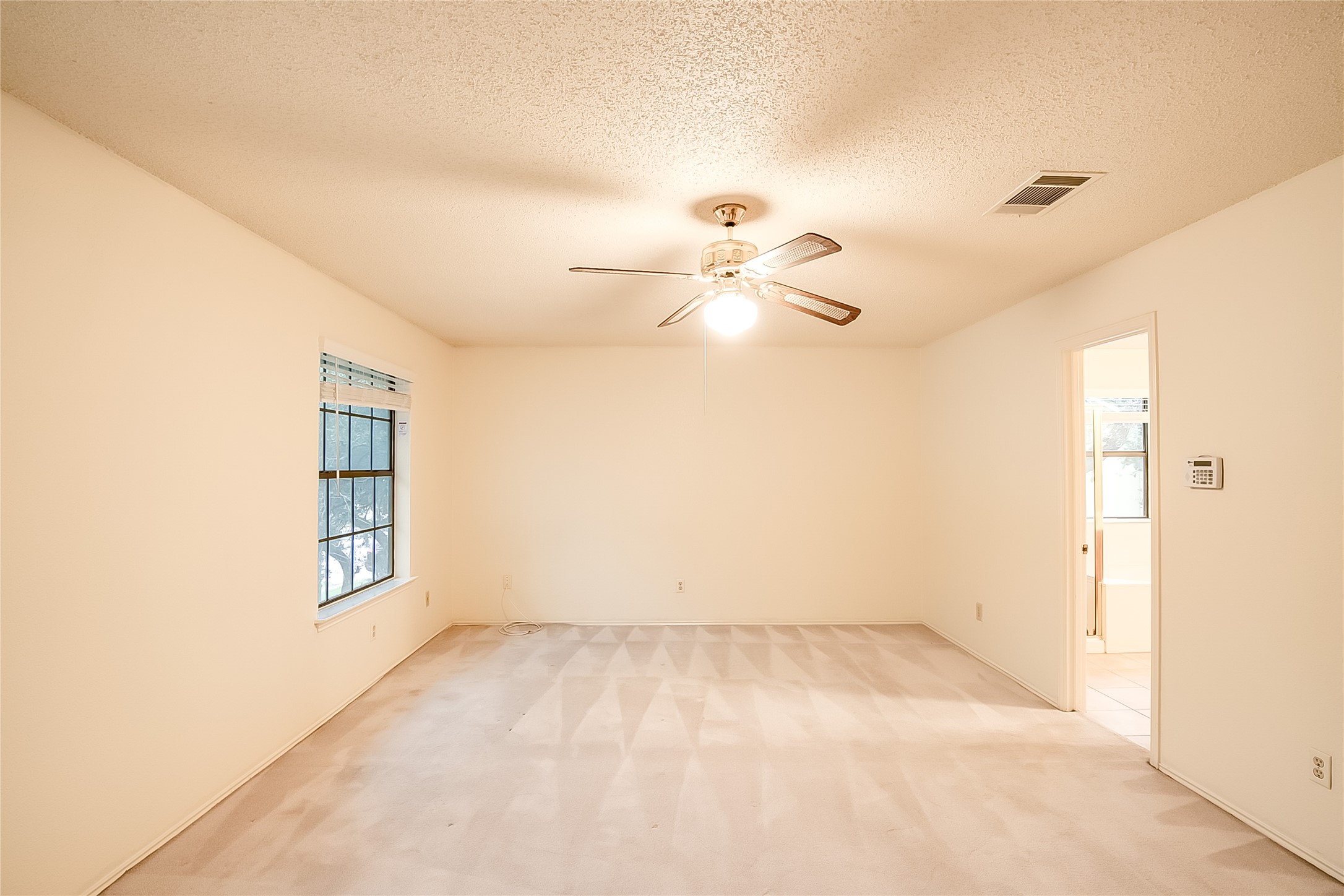 6914 Dallas Drive Austin, TX 78729 - Photo 19 of 31 an empty room with a chandelier fan and windows
