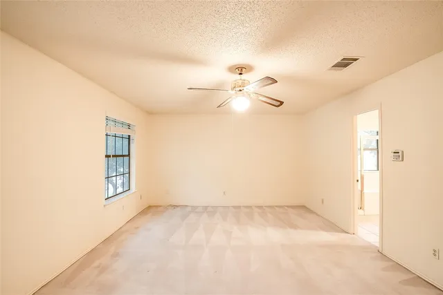 an empty room with windows and ceiling fan