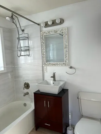 a bathroom with a bathtub sink vanity mirror and toilet