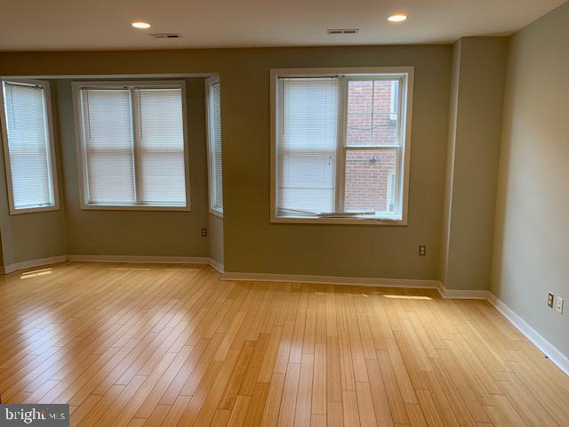 4742 Pine Street, Unit 104 Philadelphia, PA 19143 - Photo 6 of 12 an empty room with wooden floor and windows