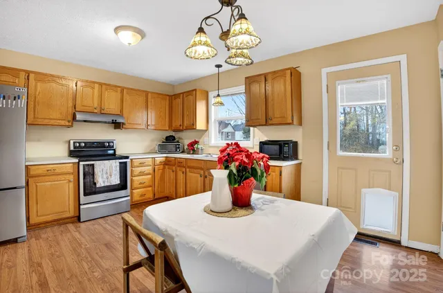 a kitchen with stainless steel appliances granite countertop a stove a sink dishwasher a microwave oven with a dining table and chairs with wooden floor