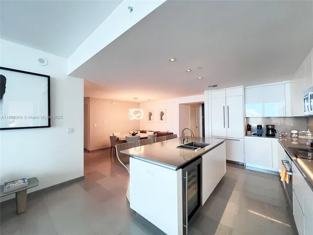 a kitchen with a stove a sink a refrigerator and white cabinets with wooden floor