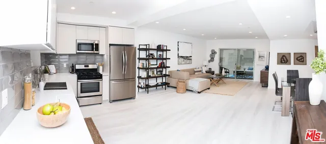 a living room with stainless steel appliances furniture and a kitchen view