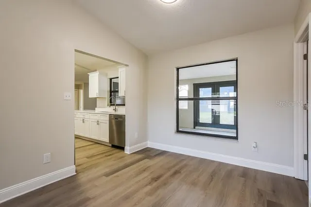 an empty room with a kitchen and wooden floor