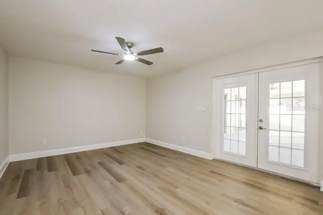 a view of empty room with wooden floor and fan