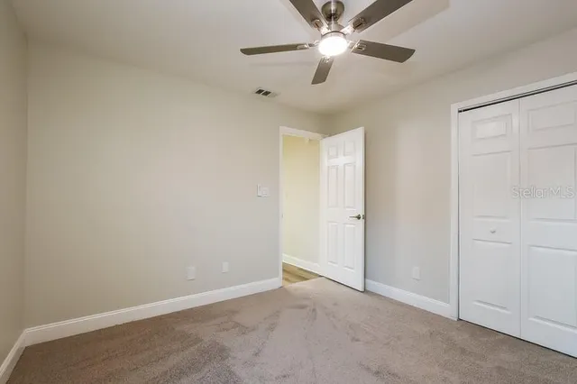 an empty room with closet and a chandelier fan