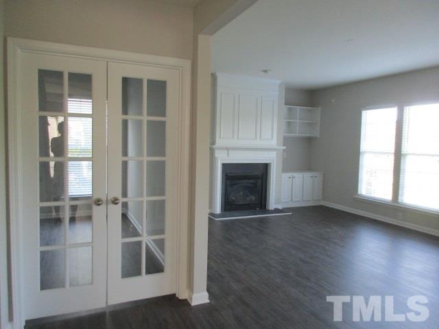 7714 San Gabriel Street Raleigh, NC 27613 - Photo 4 of 25 an empty room with wooden floor fireplace and windows
