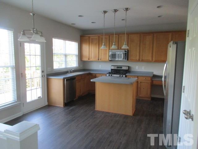 7714 San Gabriel Street Raleigh, NC 27613 - Photo 5 of 25 a kitchen with stainless steel appliances granite countertop wooden floors and white cabinets