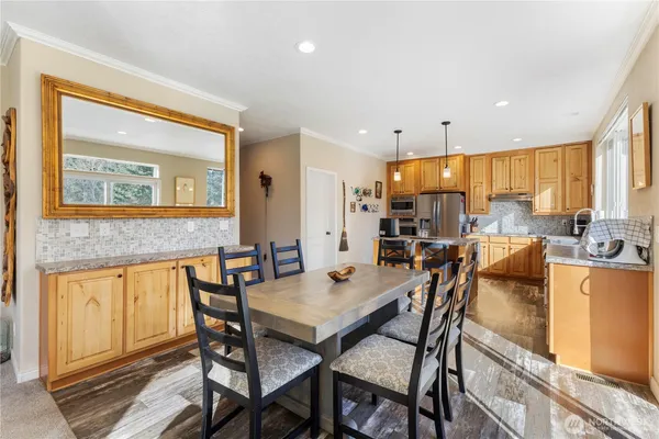 a kitchen with granite countertop a stove a sink a dining table and chairs with wooden floor