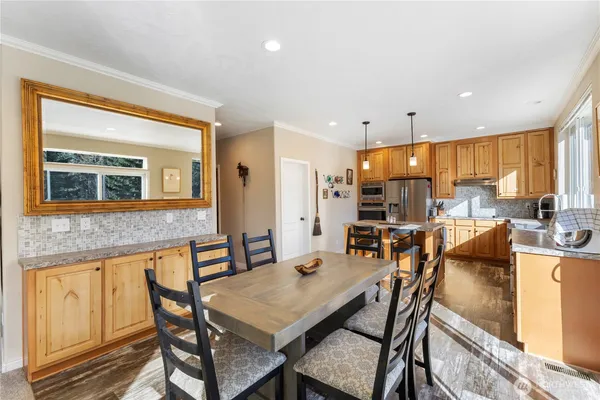 a open kitchen with stainless steel appliances granite countertop a refrigerator a sink dishwasher and a dining table with wooden floor