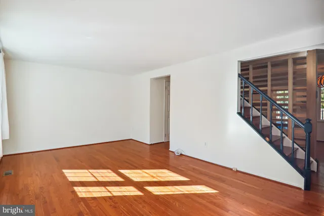 a view of an empty room with wooden floor and stairs
