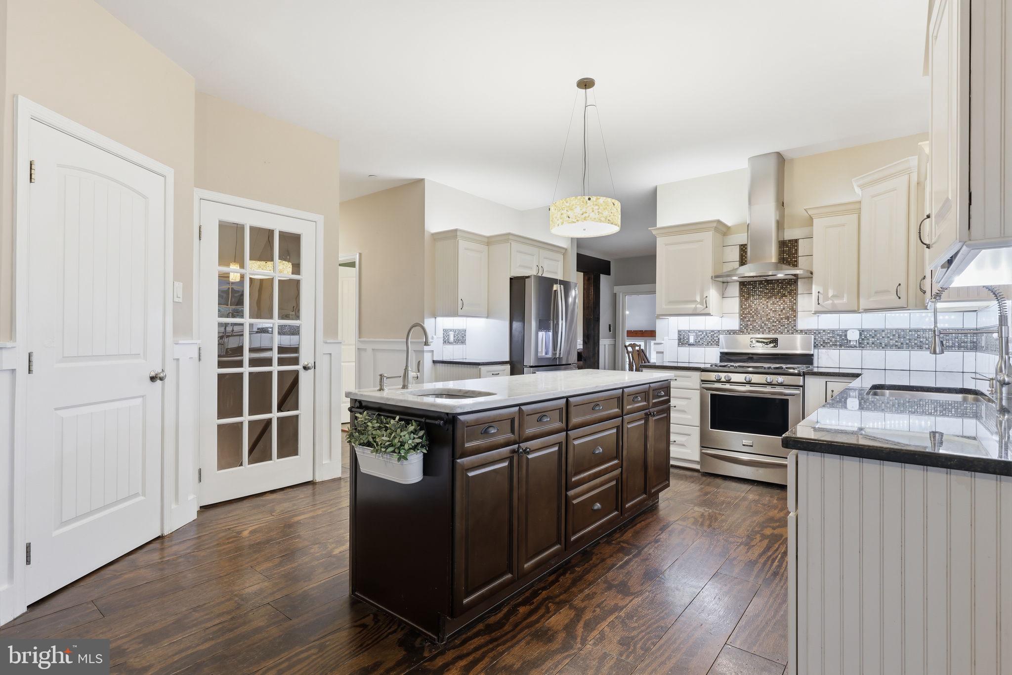 3852 Dark Hollow Road Furlong, PA 18925 - Photo 15 of 52 a kitchen with stainless steel appliances a stove a sink dishwasher a refrigerator white cabinets and wooden floor next to a window