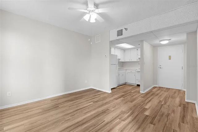 a view of a room with wooden floor and a ceiling fan