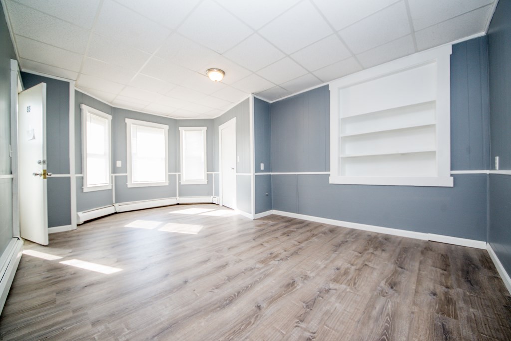 130 Baker Street Fall River, MA 02721 - Photo 7 of 21 an empty room with wooden floor cabinet and windows