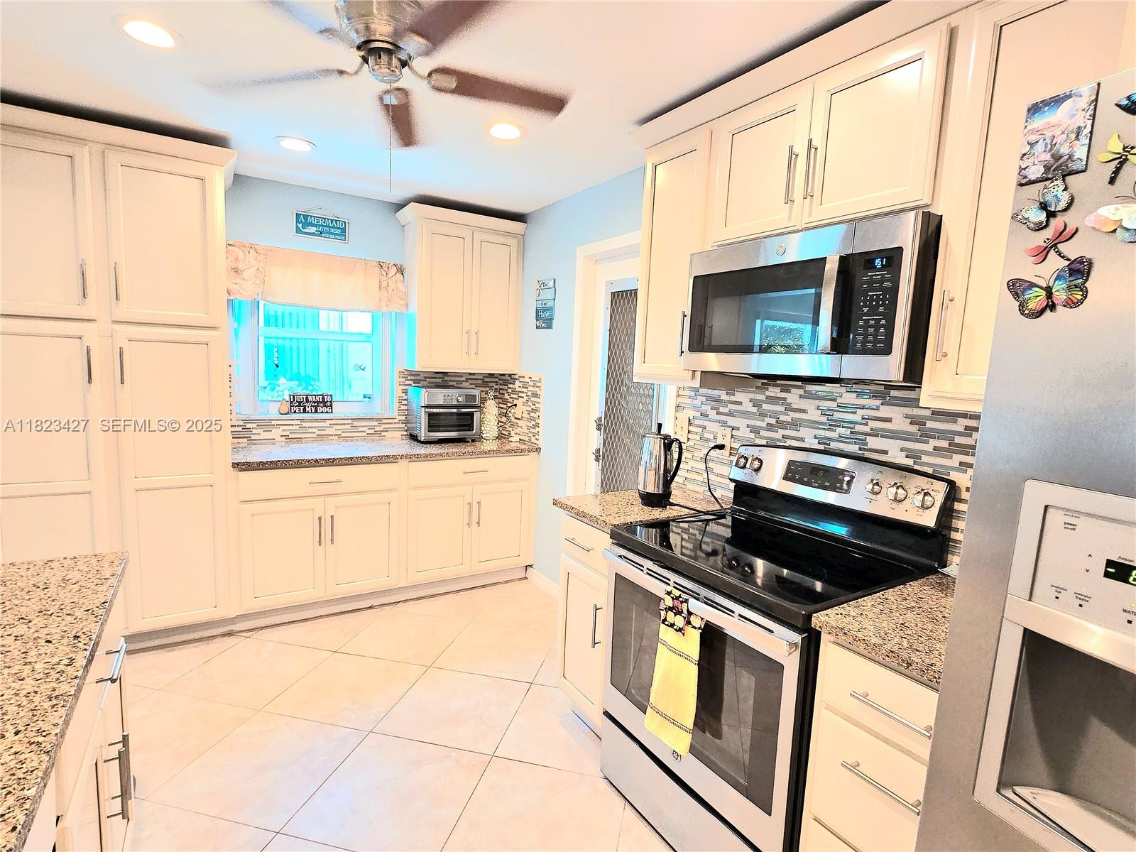 1711 Southwest 22nd Street Boynton Beach, FL 33426 - Photo 12 of 60 a kitchen with stainless steel appliances a stove microwave and cabinets