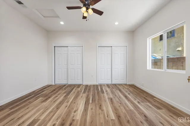 a view of a room with wooden floor ceiling fan and window