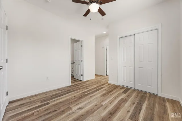 a large kitchen with stainless steel appliances granite countertop a stove a sink and white cabinets with wooden floor