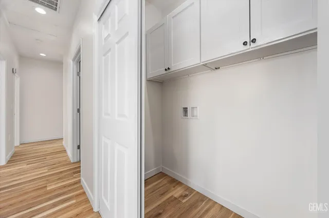 a kitchen with granite countertop white cabinets a stove a sink and dishwasher with wooden floor