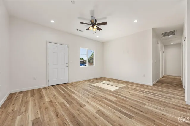 a view of empty room with wooden floor and fan