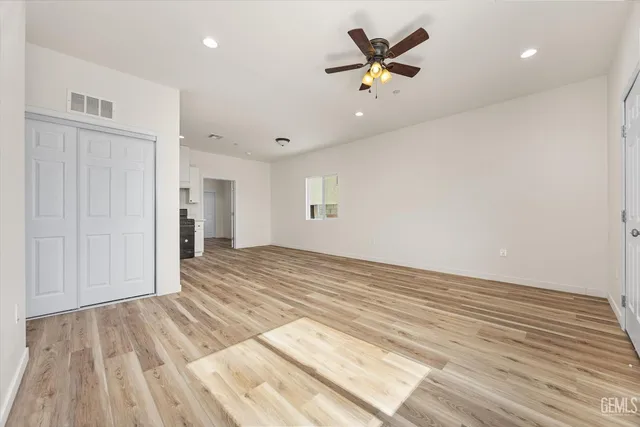a view of empty room with wooden floor and ceiling fan