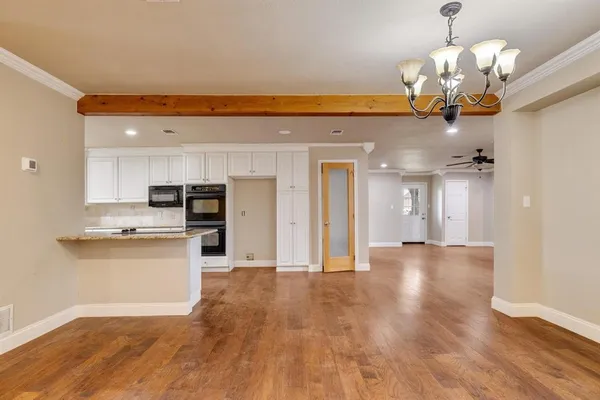 a view of a kitchen with a sink and dishwasher a stove top oven with wooden floor