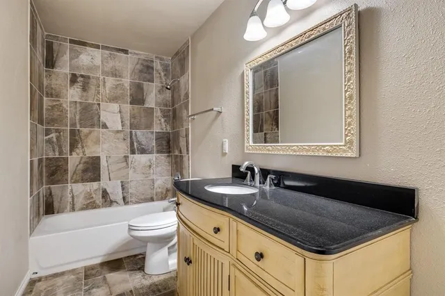 a bathroom with a granite countertop sink a toilet a mirror and shower