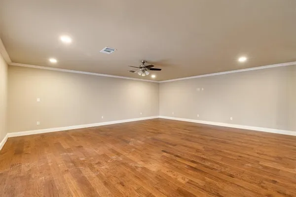 an empty room with wooden floor and fan