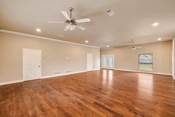 a view of an empty room with window and wooden floor