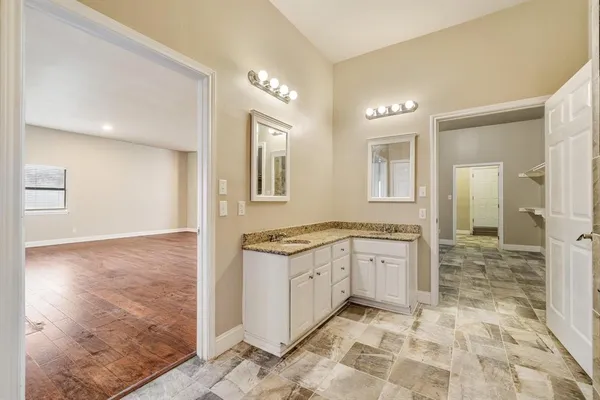 a bathroom with granite countertop a sink a toilet a mirror and shower