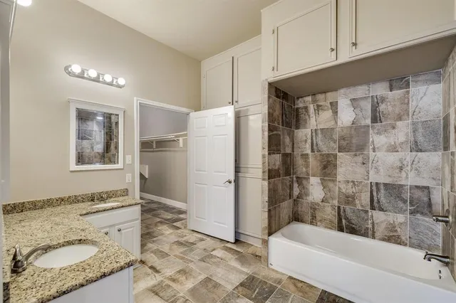 a bathroom with a granite countertop sink a toilet a shower and bathtub