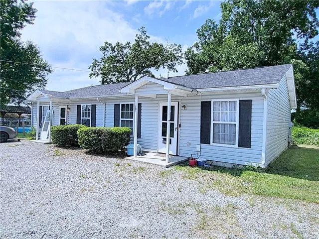 a view of a brick house with a large windows plants and large tree