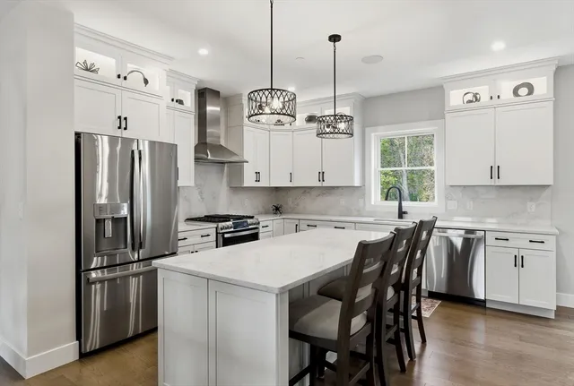 a kitchen with stainless steel appliances granite countertop a sink a stove a refrigerator and island with wooden floor