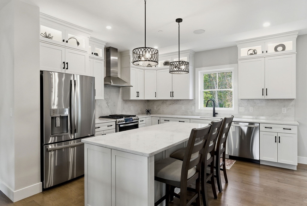 3 Elise Avenue, Unit 95 Londonderry, NH 03053 - Photo 3 of 42 a kitchen with stainless steel appliances granite countertop a sink a stove a refrigerator and island with wooden floor