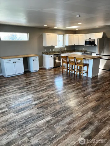 a kitchen with stainless steel appliances a dining table chairs and a wooden floor