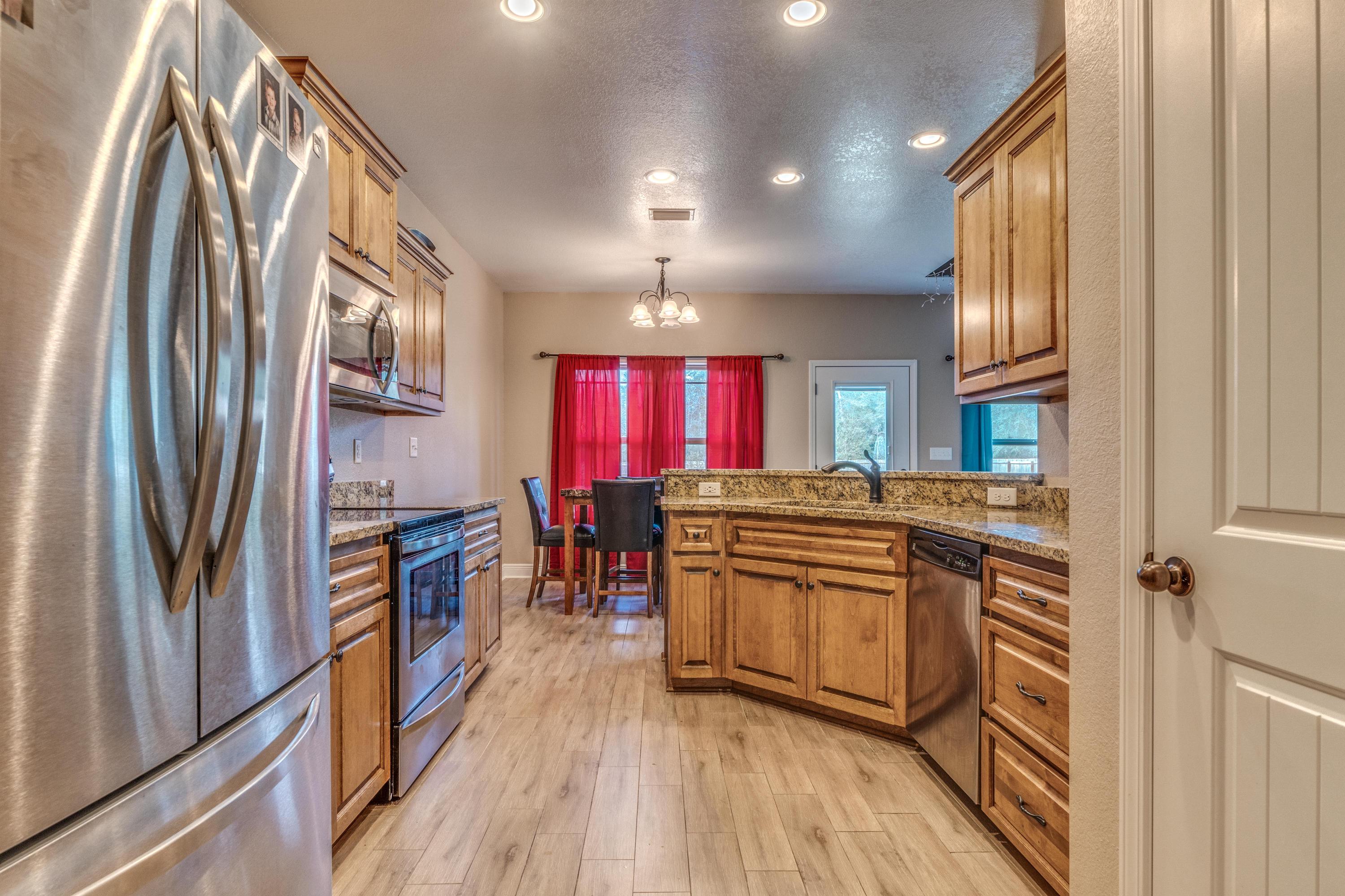 4005 Happy Trails Road Crestview, FL 32539 - Photo 8 of 24 a kitchen with stainless steel appliances granite countertop a refrigerator a stove a sink and a refrigerator with wooden floor