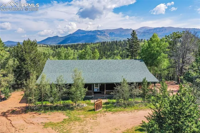 an aerial view of a house with a yard fire pit and trees in the background