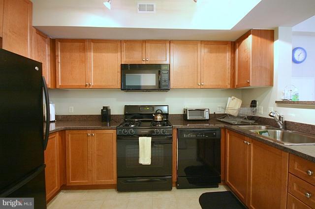 851 North Glebe Road, Unit 810 Arlington, VA 22203 - Photo 14 of 28 a kitchen with stainless steel appliances granite countertop a stove a sink dishwasher and a refrigerator with wooden cabinets
