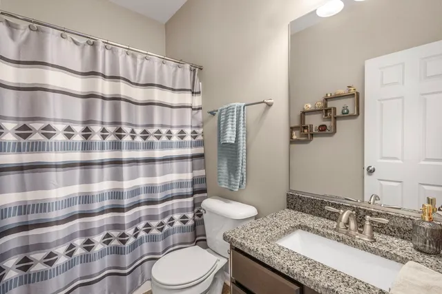 a bathroom with a granite countertop toilet a sink and a mirror
