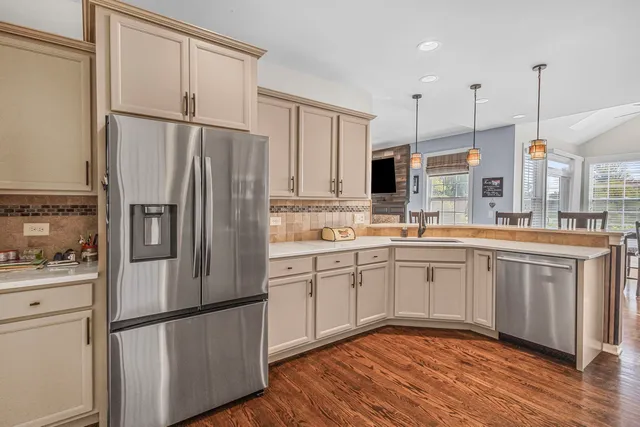 a kitchen with stainless steel appliances granite countertop a refrigerator a sink and white cabinets