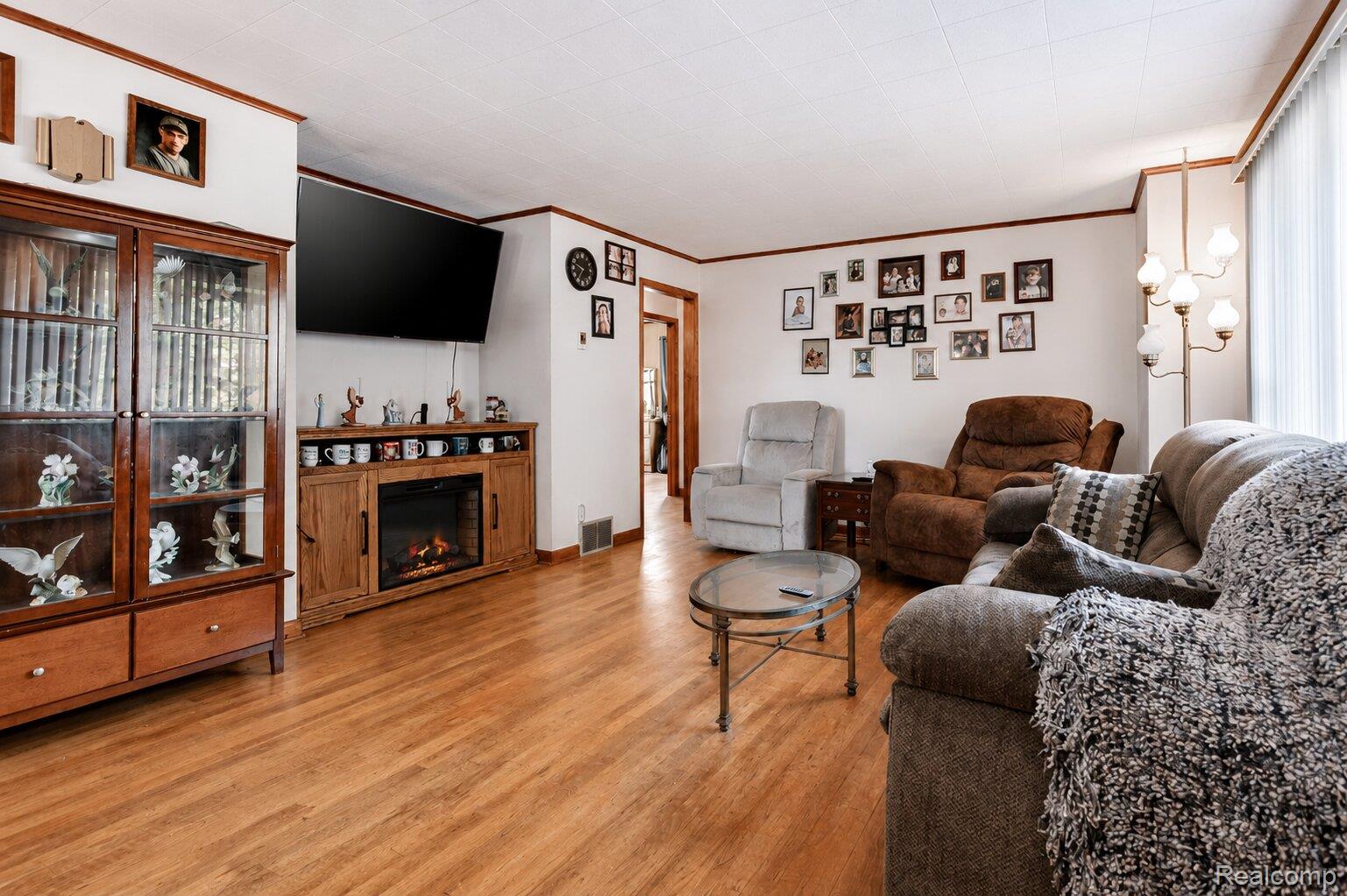 6373 Norman Road Jeddo, MI 48032 - Photo 3 of 32 Living area featuring light wood-style flooring, a warm lit fireplace, and crown molding