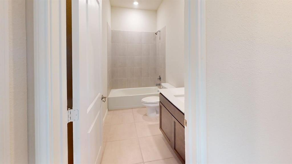 1306 Colonial Bluff Lane Princeton, TX 75407 - Photo 20 of 27 Bathroom with a tub/shower combination, light-toned wall tiling, and a vanity with a white countertop and wood-finish cabinetry