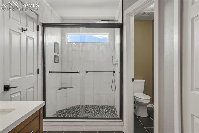 8035 Ferguson Road Peyton, CO 80831 - Photo 26 of 28 Bathroom with tile patterned flooring, vanity, toilet, and a shower with shower door