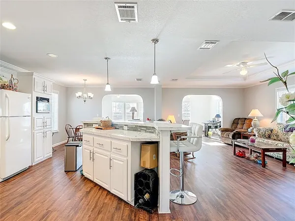 a large kitchen with granite countertop a stove a island a dining table and chairs