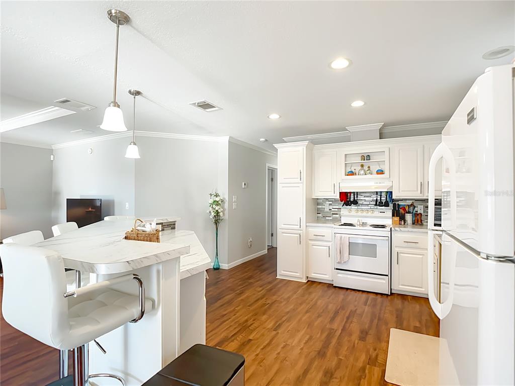1824 Riverside Drive Moore Haven, FL 33471 - Photo 21 of 66 a kitchen with a stove a refrigerator and white cabinets with wooden floor