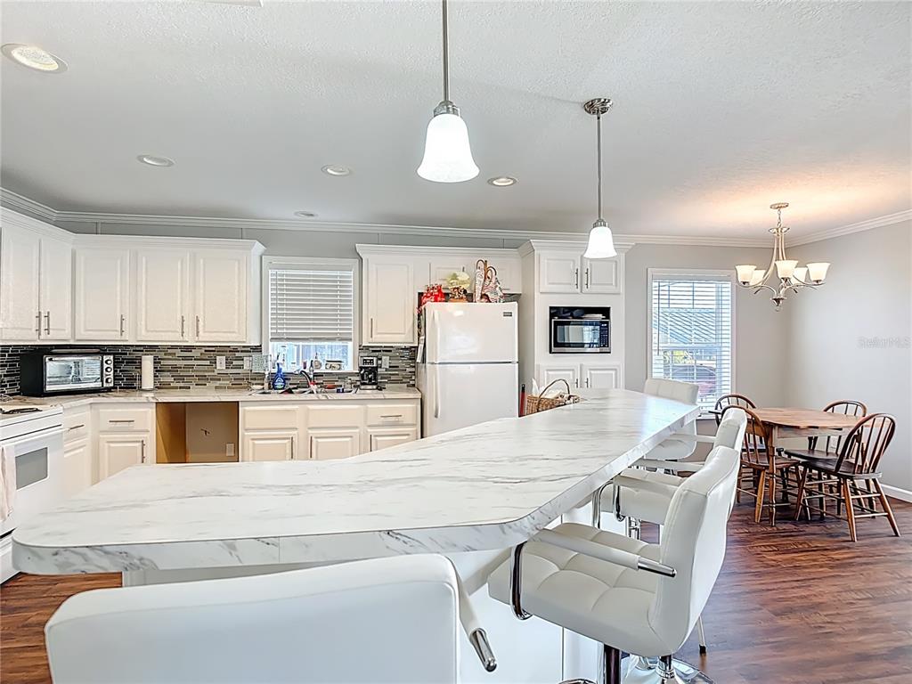 1824 Riverside Drive Moore Haven, FL 33471 - Photo 22 of 66 a large kitchen with granite countertop a stove a island a dining table and chairs