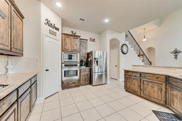 a kitchen with stainless steel appliances granite countertop a refrigerator and a stove top oven