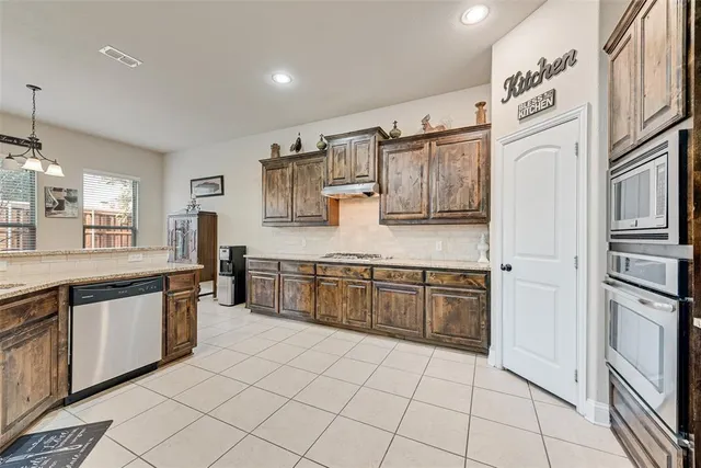 a large kitchen with stainless steel appliances granite countertop a sink and dishwasher a refrigerator with wooden cabinets