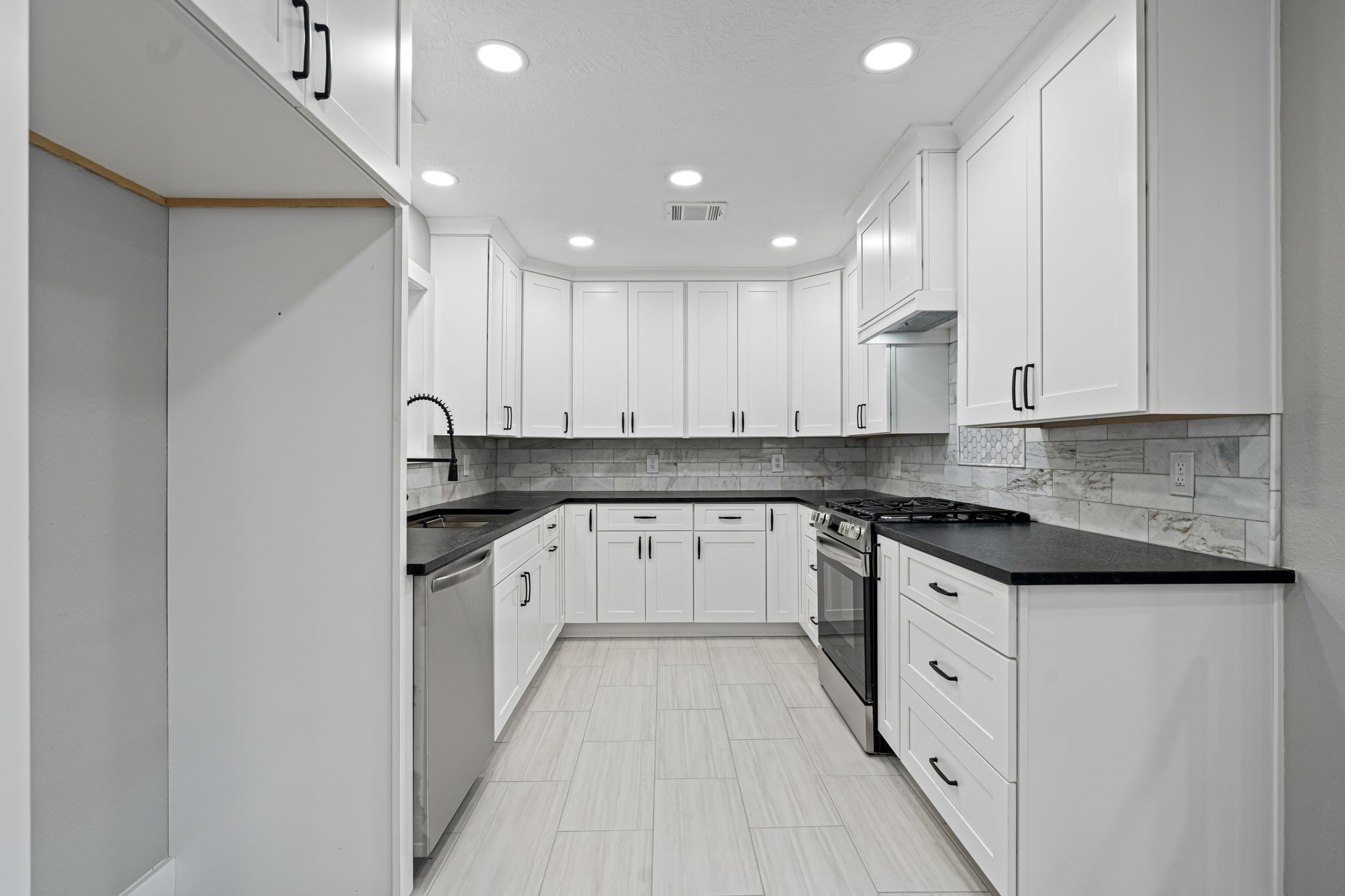 284 Hackberry Street Trinity, TX 75862 - Photo 5 of 42 The kitchen is fitted with Shaker-style cabinetry with custom additions, leathered granite countertops, subway-style backsplash, updated LED lighting, and undermount contemporary stainless-steel sink and appliances.