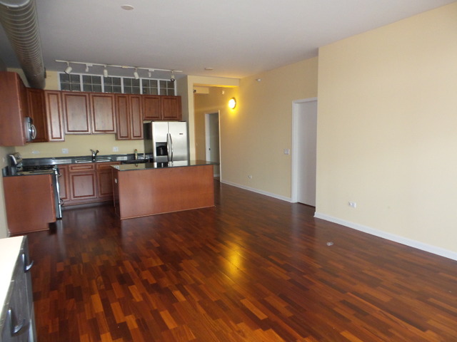 1200 West Monroe Street, Unit 803 Chicago, IL 60607 - Photo 3 of 12 a kitchen with granite countertop wooden floors and stainless steel appliances